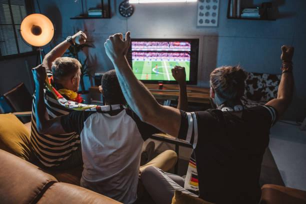 Sports fan watching a football match on television at home, illustrating the experience of using a sports streaming service.